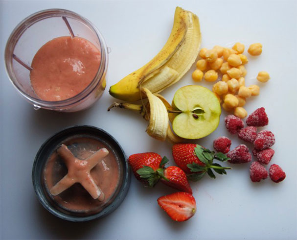 Smoothie ingredients, including chickpeas, on a table with a blender