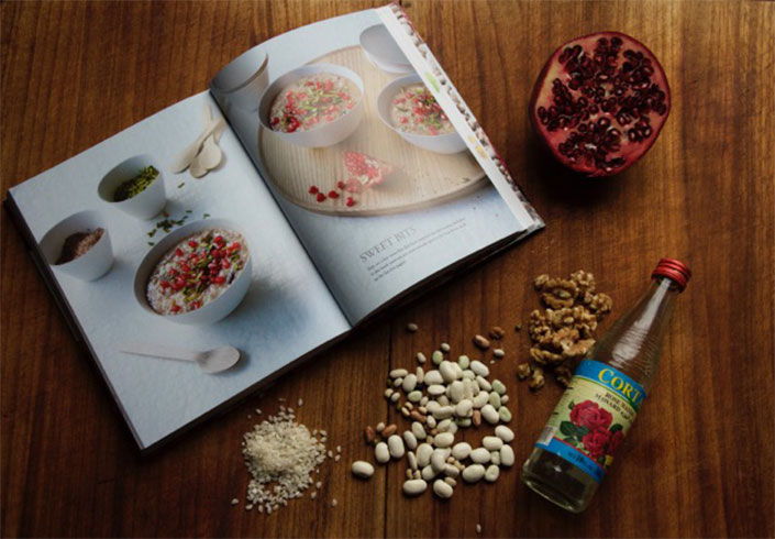 An open book showing a Sweet Bits page, on a table with beans and other ingredients